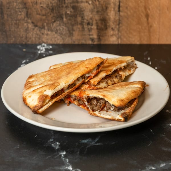 Four pieces of baked quesadilla-like bread filled with ground meat, cheese, and sauce on a white plate.