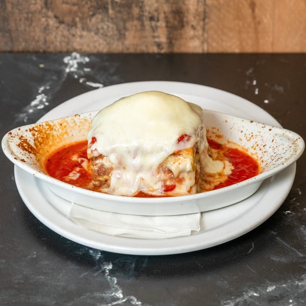 Piccolo Pizza & More's lasagna, baked in a white dish with melted mozzarella and rich tomato sauce.